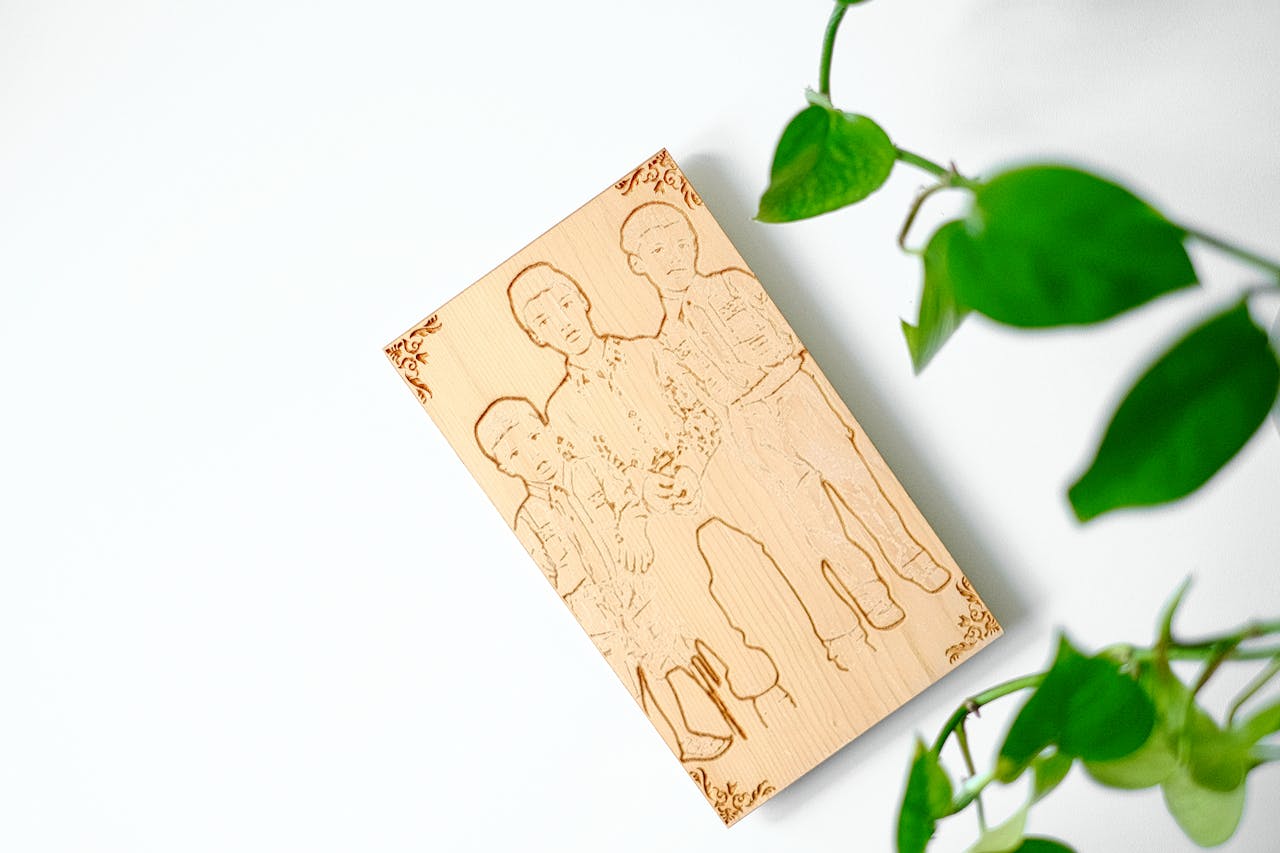 services-02 A minimalist wooden engraving art piece surrounded by green leaves on a white background.