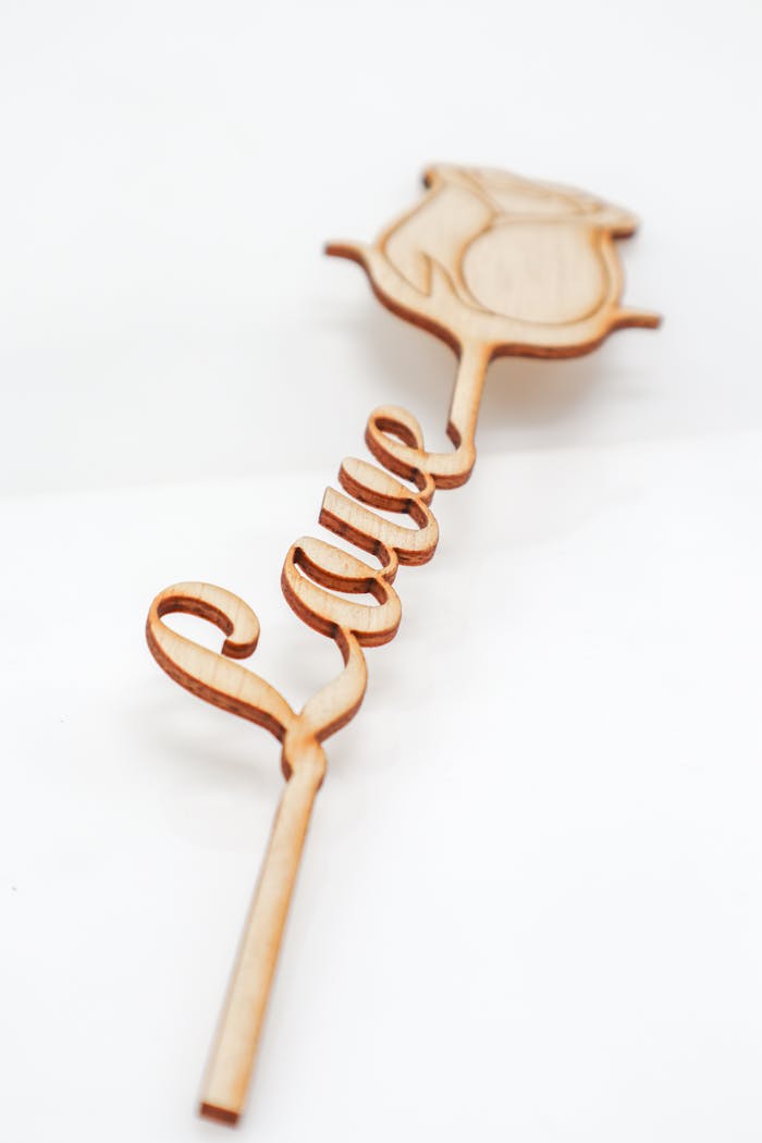 hero-img-01 Elegant wooden stick with rose design spelling 'Love' in a script style.